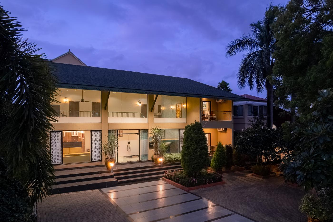 Amaltas Villa at dusk, lit from inside, with palms around it